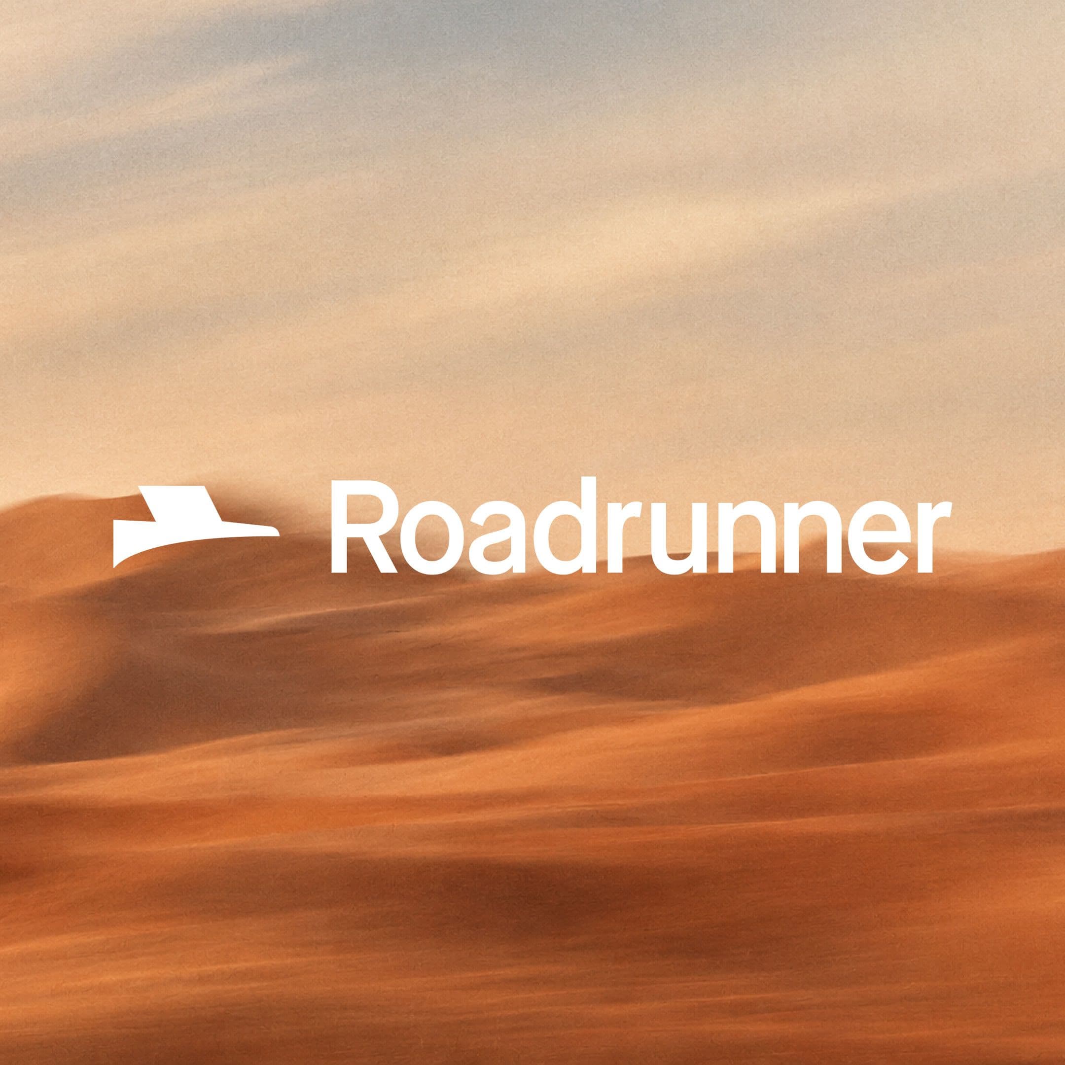 The Roadrunner logo over desert sand dunes at dusk